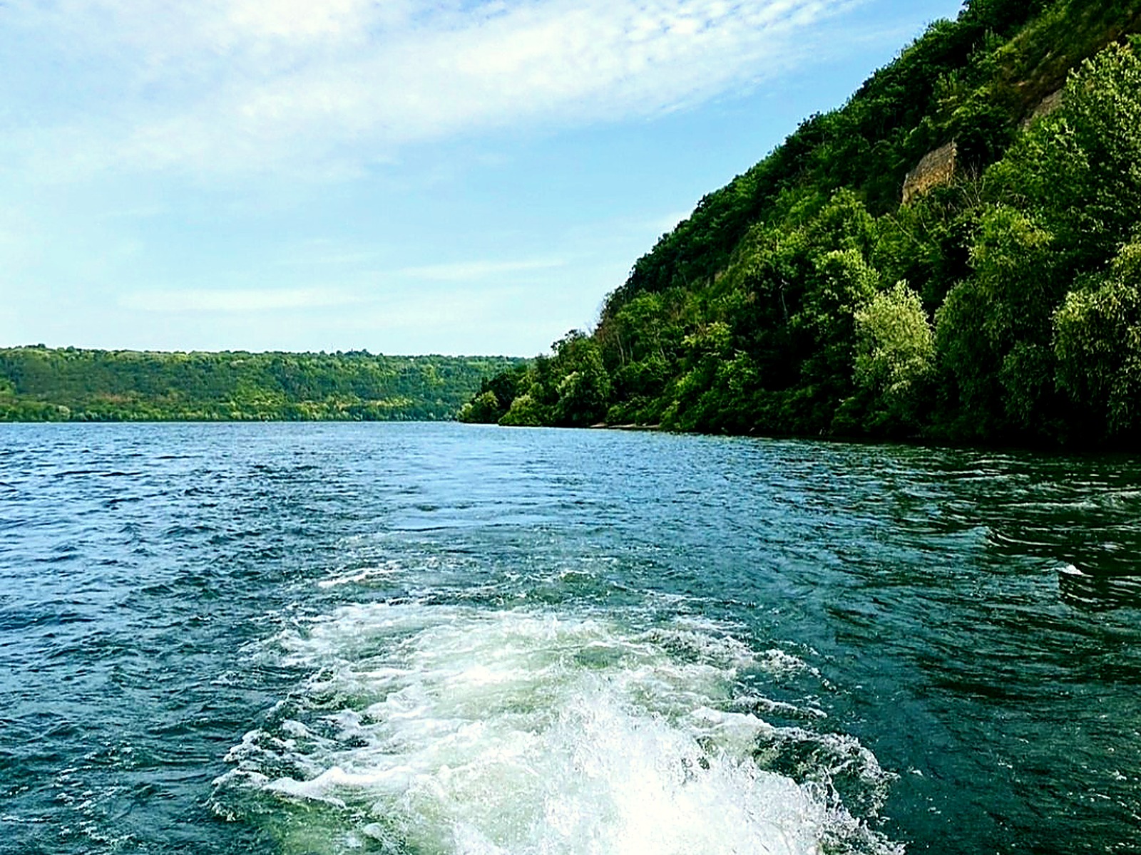 Каньйон Дністра з човна: зелені схили та слід від катера на воді